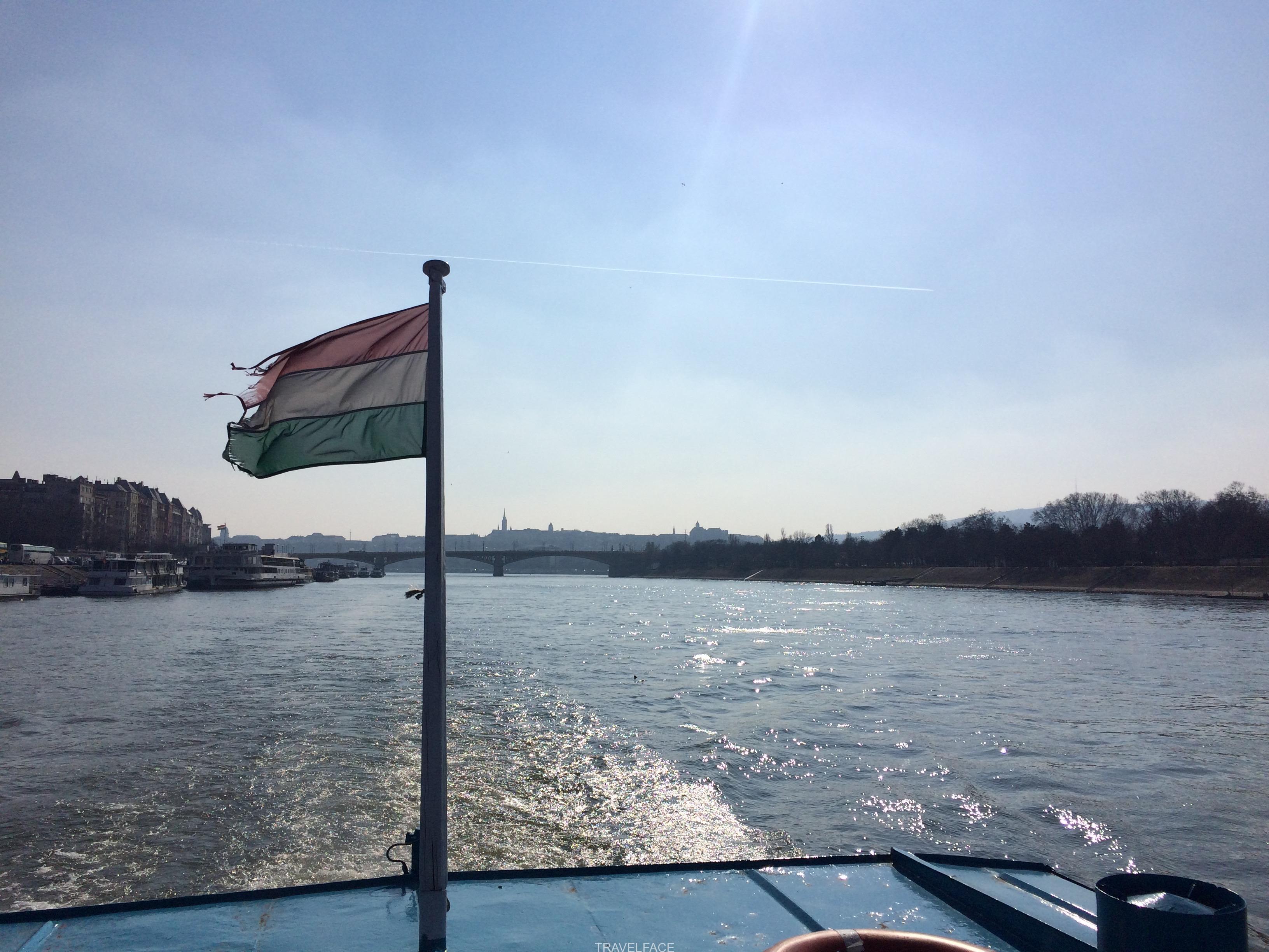 Hungarian flag blowing on back of boat along river
